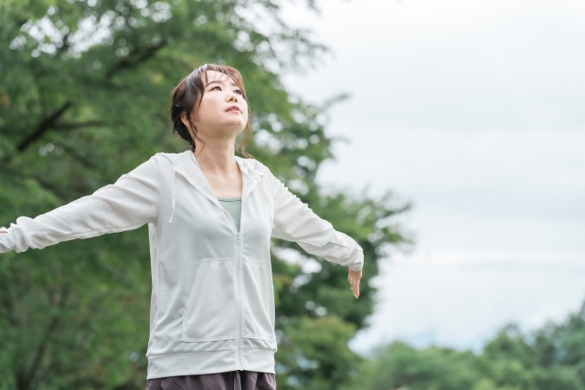 花粉症が改善し屋外で深呼吸する女性 | 脳活整体ルーム APLO(アプロ)